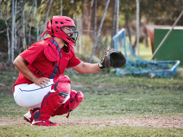 A baseball catcher wearing a uniform with white pants