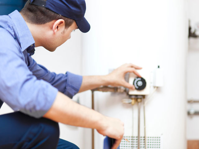 A maintenance man checking why a hot water heater ran out of hot water