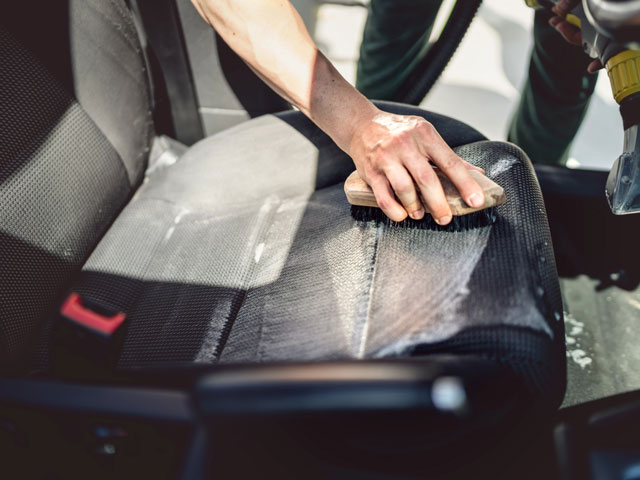 A person scrubbing a car seat to clean it