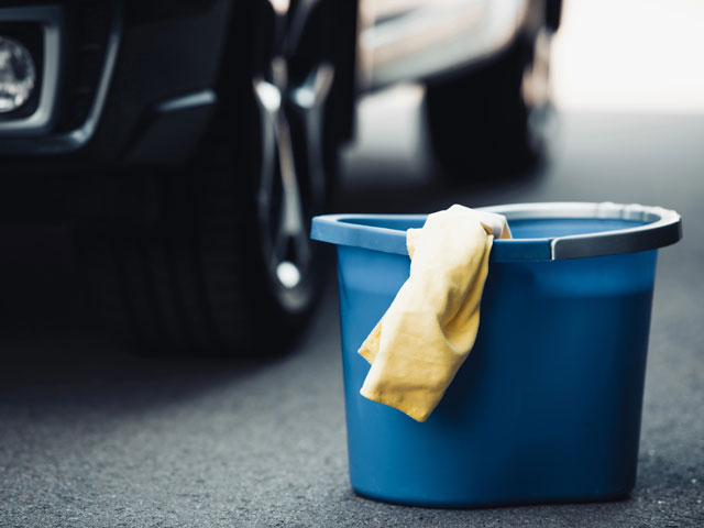 A bucket of soapy water resting next to a classic car