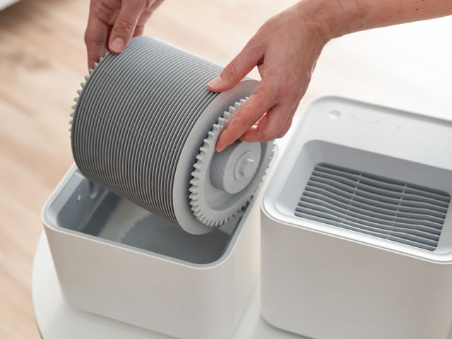 A person removing the air filter on their humidifier for cleaning