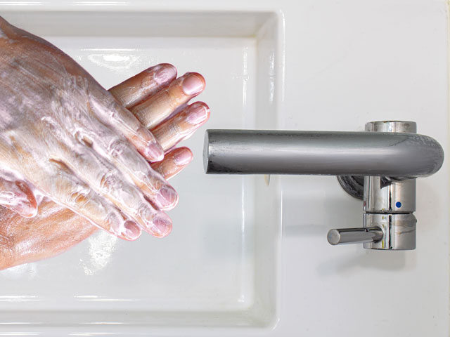 A person washing their hands prior to drying them